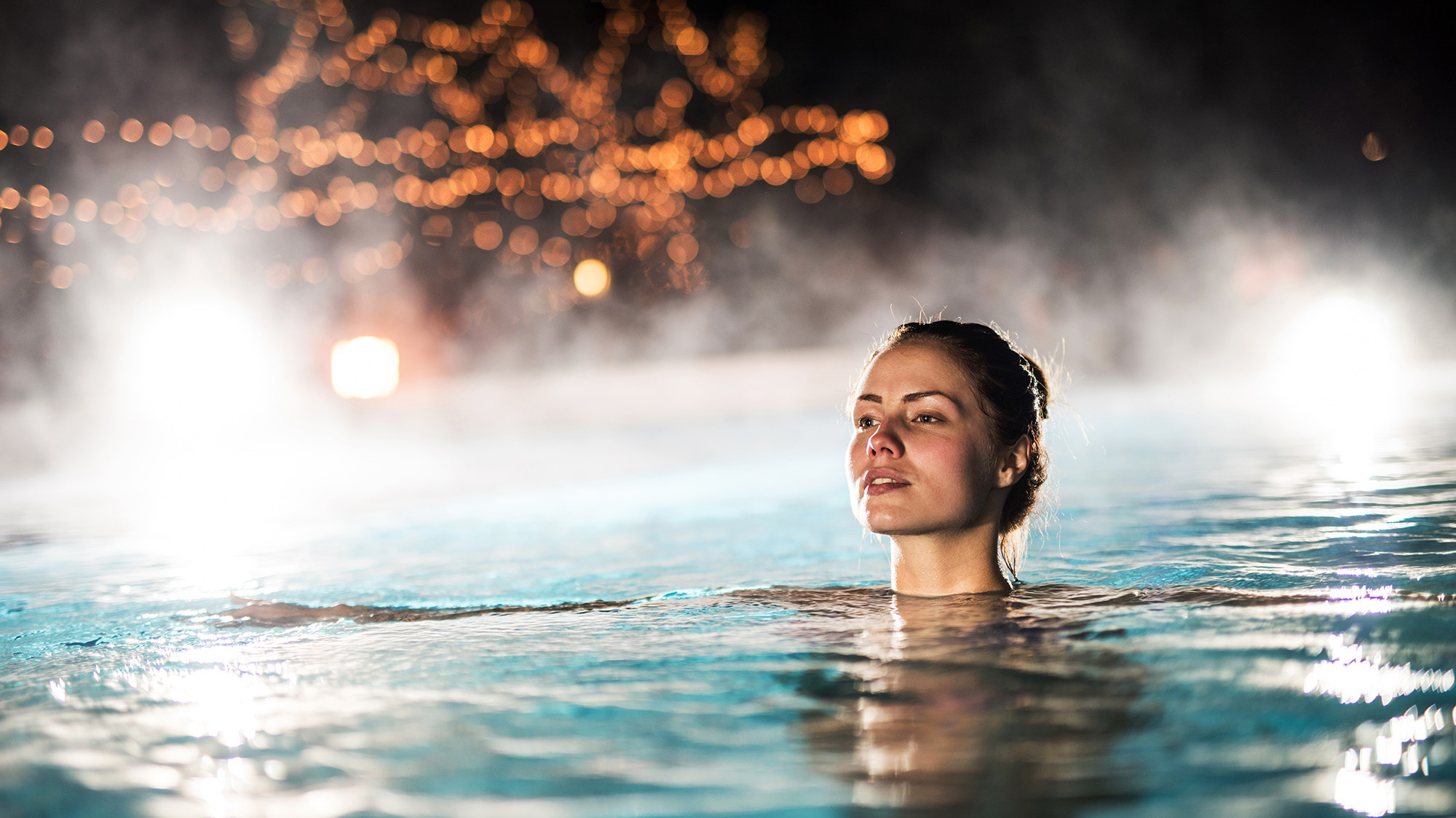 Frau schwimmt im Winter in einem heißen Pool