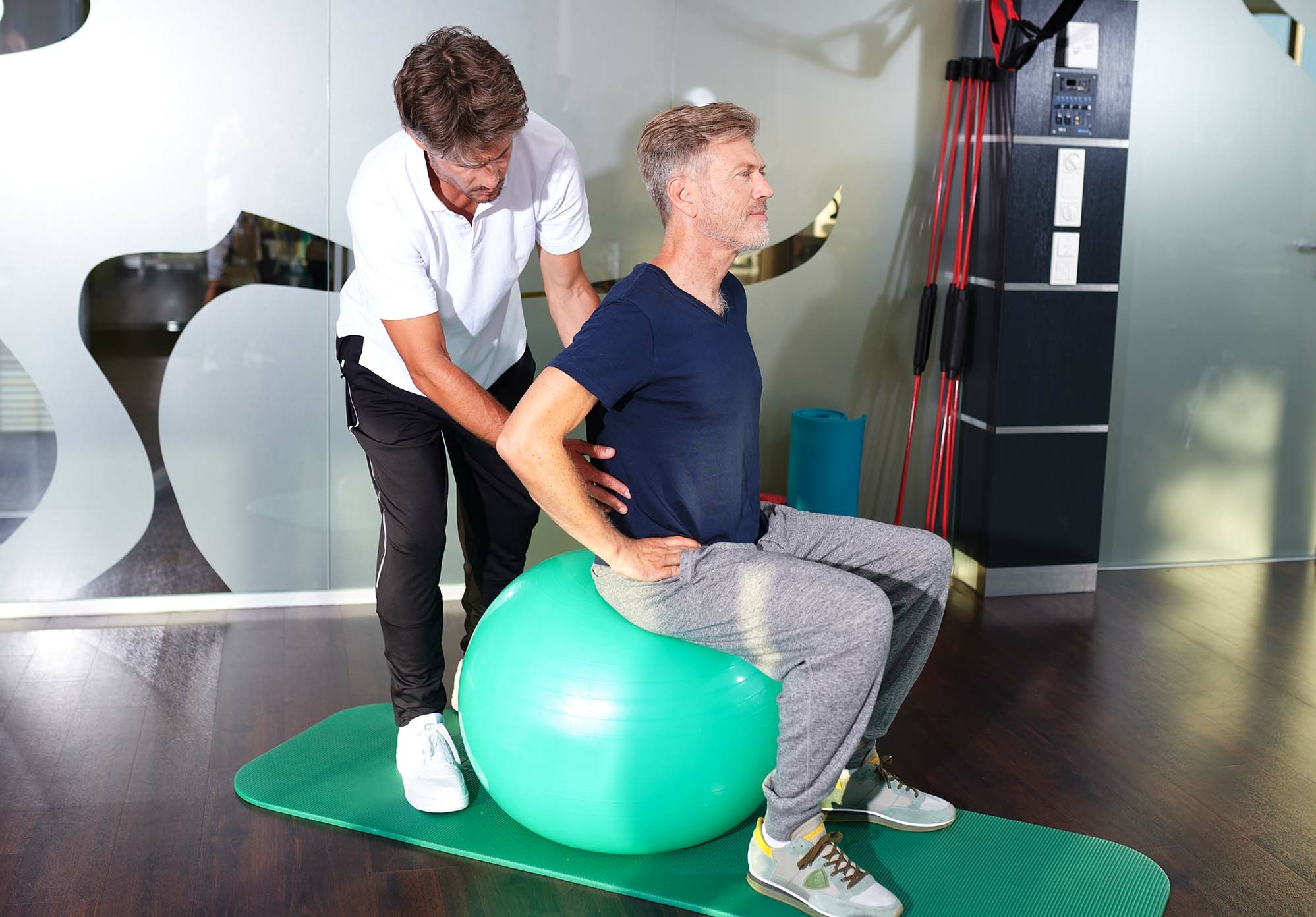 Krankengymnastik mit Trainer und Gymnastikball